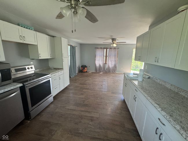 kitchen with white cabinetry, a ceiling fan, appliances with stainless steel finishes, and dark wood-type flooring | Image 10