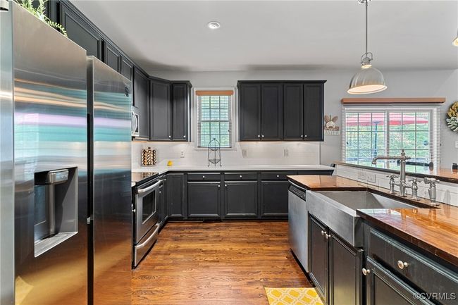 Kitchen with dark wood finished floors, stainless steel appliances, backsplash, a sink, and pendant lighting | Image 5