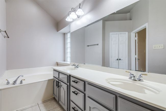 Bathroom with double vanity, a bath, tile patterned flooring, and lofted ceiling | Image 22