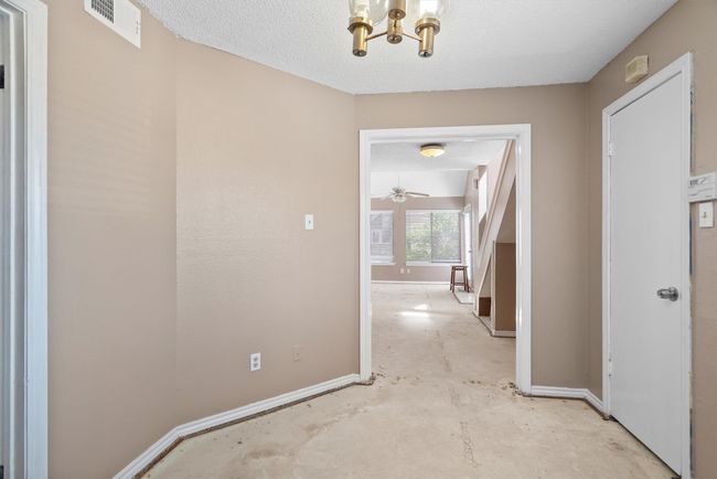 Corridor featuring a chandelier, concrete floors, and a textured ceiling | Image 8