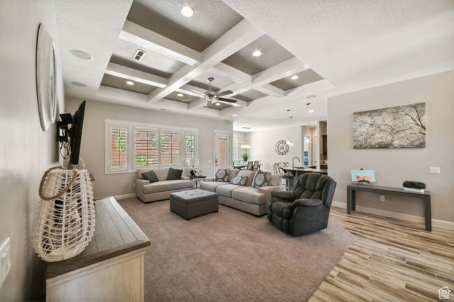 Living room featuring light wood finished floors, coffered ceiling, a ceiling fan, beamed ceiling, and baseboards | Image 9