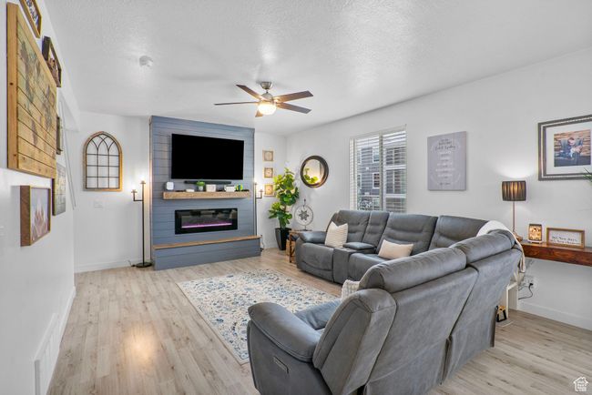 Living room with baseboards, light wood-type flooring, a ceiling fan, and a large fireplace | Image 27