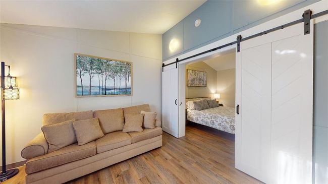 Living room with a barn door and wood finished floors | Image 18