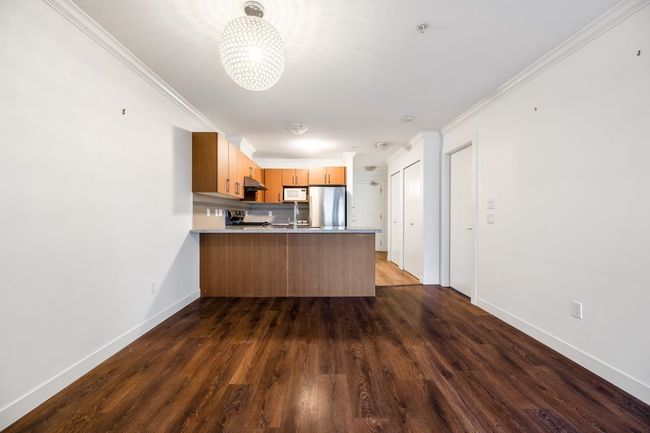 Kitchen with freestanding refrigerator, white microwave, a peninsula, a chandelier, and dark wood-style flooring | Image 8