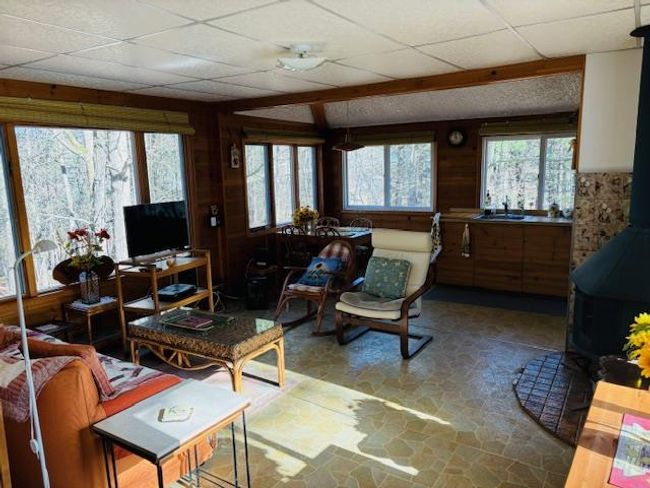 Living room featuring a drop ceiling, wood walls, and sink | Image 6