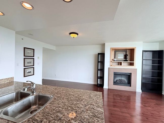Kitchen with dark wood finished floors, a fireplace, recessed lighting, and stone countertops | Image 10