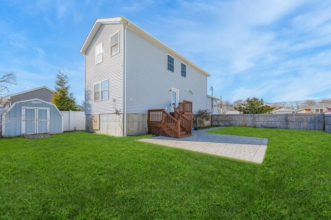 Back of property with an outbuilding, a fenced backyard, a storage unit, a yard, and a patio area | Image 4