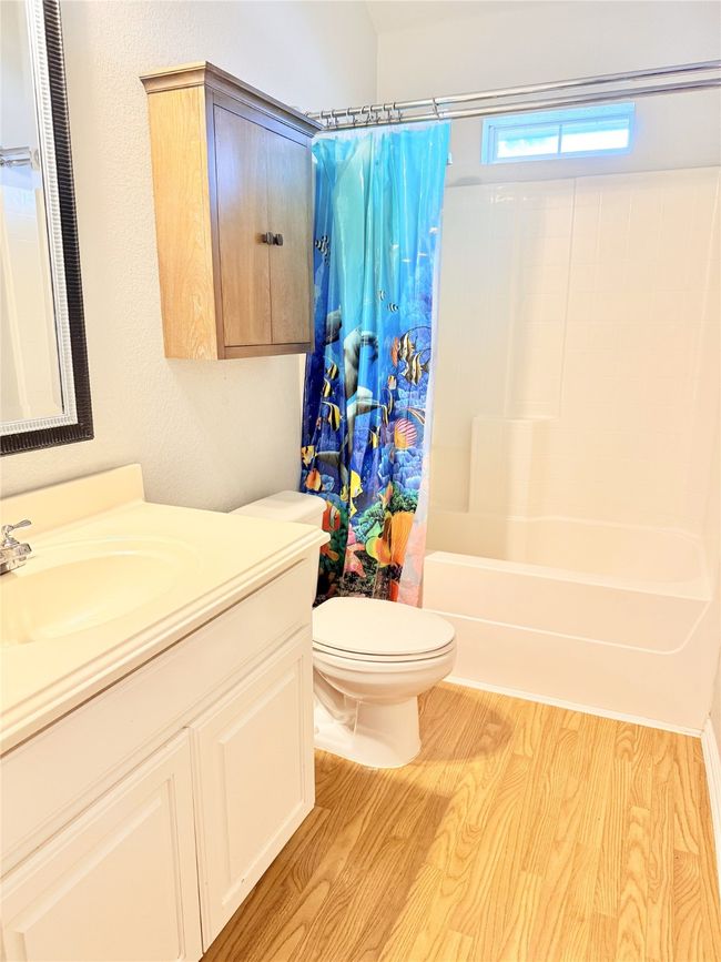 Full bathroom featuring toilet, wood finished floors, vanity, and shower / bath combo with shower curtain | Image 17