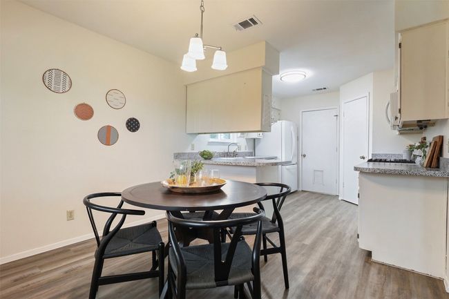 Dining room with view of kitchen and garage entry in the background. | Image 10