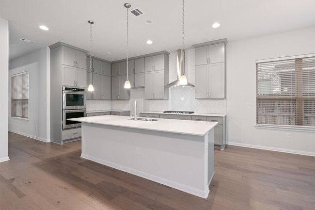Kitchen with visible vents, wall chimney exhaust hood, appliances with stainless steel finishes, dark wood-style floors, and gray cabinets | Image 11