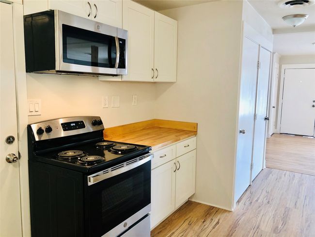 Kitchen featuring stainless steel appliances, light wood-type flooring, and white cabinetry | Image 21