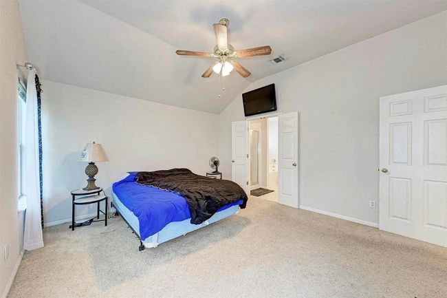 Carpeted bedroom featuring vaulted ceiling, a ceiling fan, and connected bathroom | Image 4