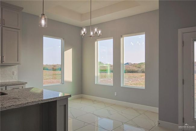 Unfurnished dining area featuring a notable chandelier and a tray ceiling | Image 4