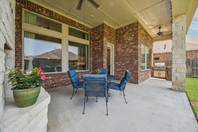 Outdoor living space w/ covered patio, fan, and gaslog fireplace. You'll find a full outdoor kitchen equipped with a Solaire infrared grill, mini fridge and ample storage with a granite top. | Image 29