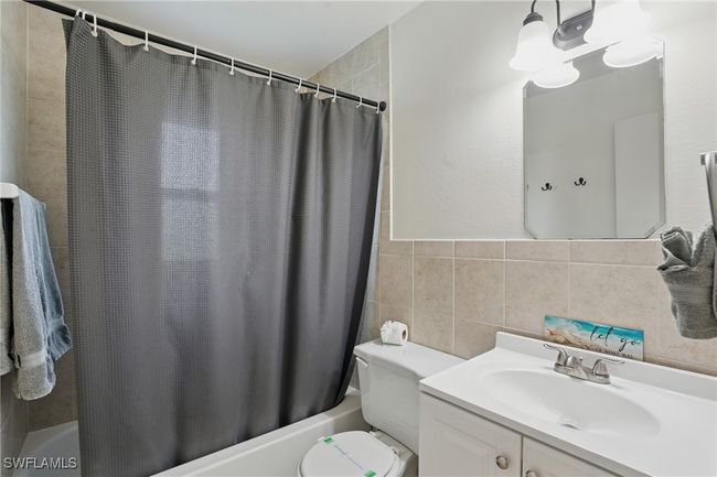 Bathroom featuring shower / bath combo, vanity, and tile walls | Image 29