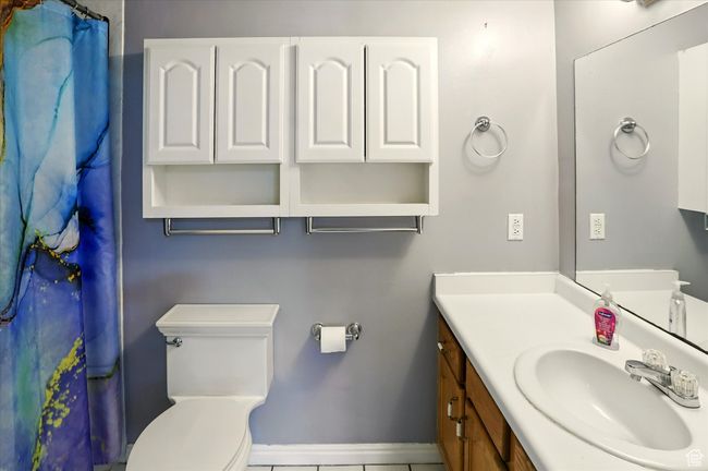 Full bathroom with vanity, toilet, tile patterned flooring, baseboards, and curtained shower | Image 13