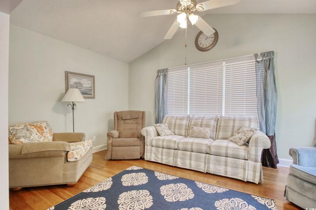 Living area with vaulted ceiling, a ceiling fan, and wood finished floors | Image 18
