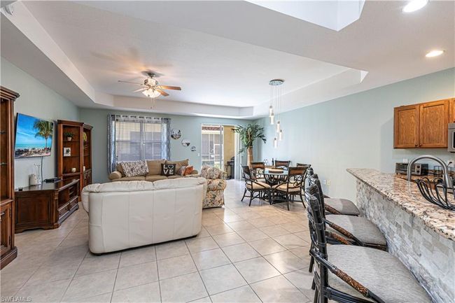 Living area with recessed lighting, a tray ceiling, light tile patterned flooring, and ceiling fan | Image 5