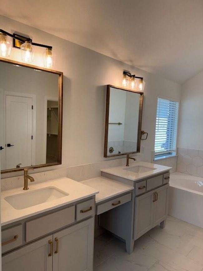 Full bath featuring a garden tub, marble finish floor, a sink, and two vanities | Image 21