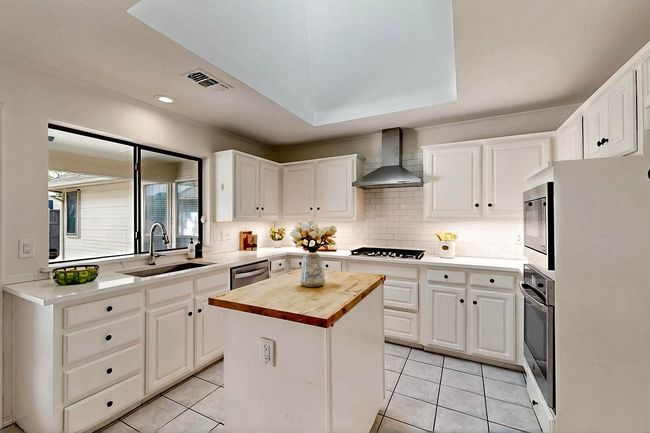Kitchen featuring butcher block counters, white cabinetry, light tile patterned floors, and recessed lighting | Image 8