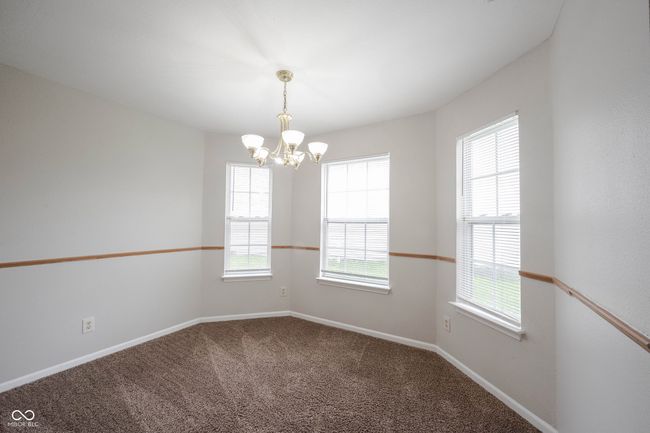 carpeted empty room with baseboards and a chandelier | Image 11