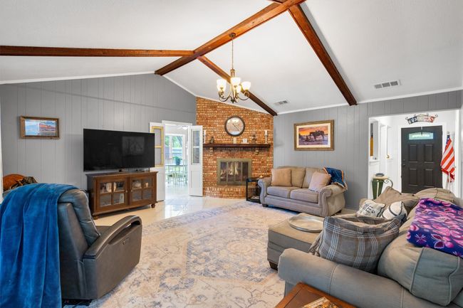 Double doors lead to the kitchen with front door to the right. Beautiful wood burning fireplace. | Image 6