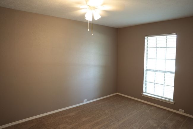 Spare room featuring a ceiling fan and dark colored carpet | Image 8