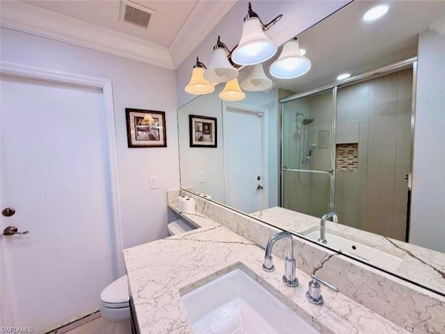 Bathroom featuring visible vents, a stall shower, toilet, ornamental molding, and vanity | Image 24