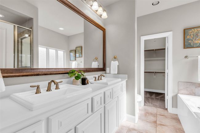 Bathroom with a shower stall, a garden tub, double vanity, baseboards, and a walk in closet | Image 17