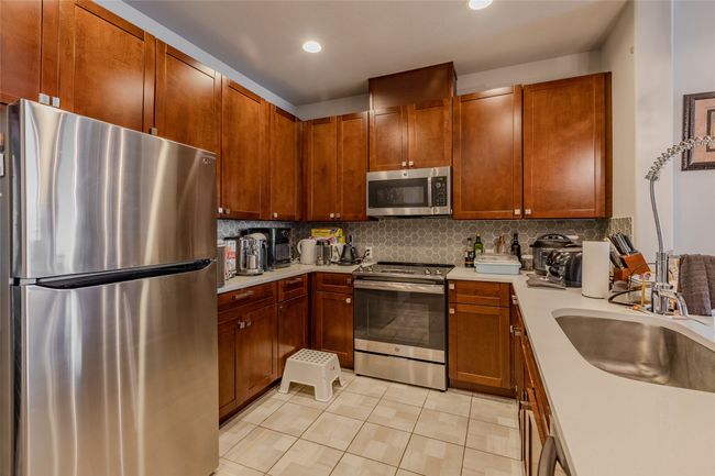 Kitchen with appliances with stainless steel finishes, light countertops, light tile patterned floors, decorative backsplash, and recessed lighting | Image 13