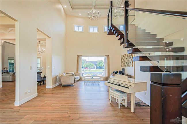 Entryway featuring a chandelier, porcelain floors, crown molding, metal beam, solid maple floating steps wood and clear glass railings | Image 6