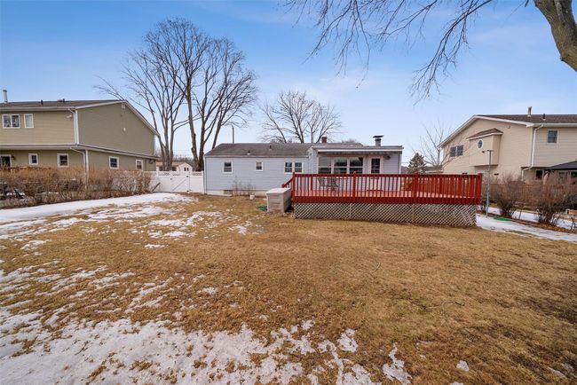Snow covered house featuring a residential view, fence, a deck, and a lawn | Image 43