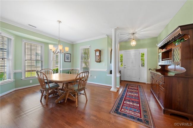 Dining space featuring decorative columns, healthy amount of natural light, dark wood-style flooring, and ornamental molding | Image 8