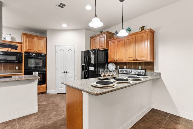 Kitchen with baseboards, backsplash, black appliances, and tile patterned flooring | Image 10