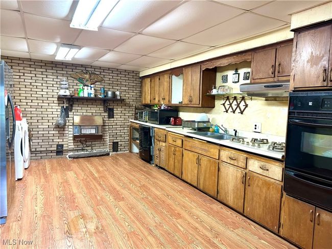 Kitchen with oven, a drop ceiling, a warming drawer, light wood-style flooring, and under cabinet range hood | Image 11