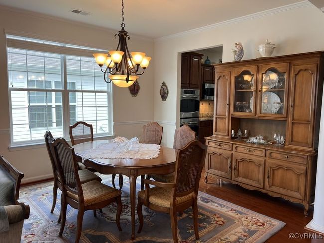 Dining space featuring ornamental molding, dark wood-type flooring, and a chandelier | Image 12