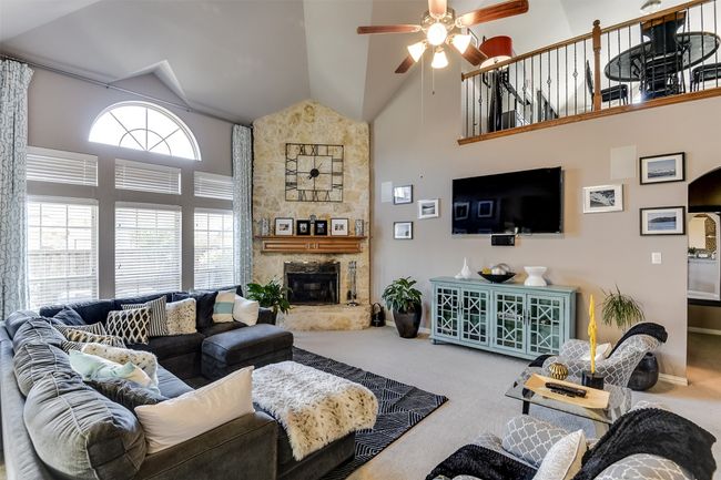 Carpeted living room featuring ceiling fan, a fireplace, and high vaulted ceiling | Image 11