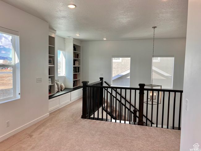 Hall with carpet, a textured ceiling, an inviting chandelier, and built in shelves | Image 12