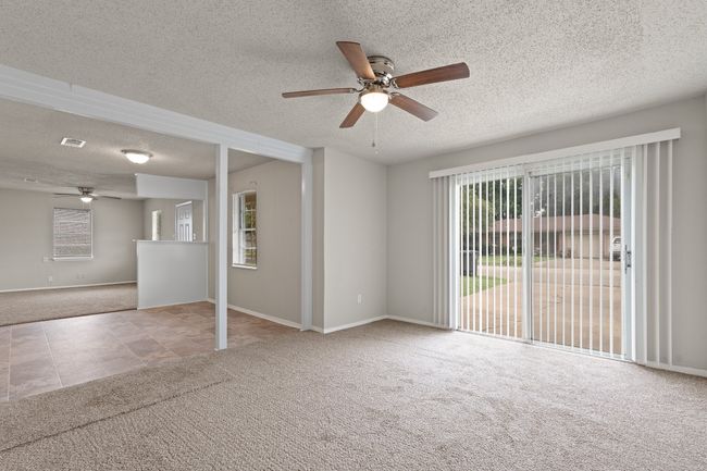 Spare room featuring carpet, a ceiling fan, a textured ceiling, healthy amount of natural light, and tile patterned floors | Image 10