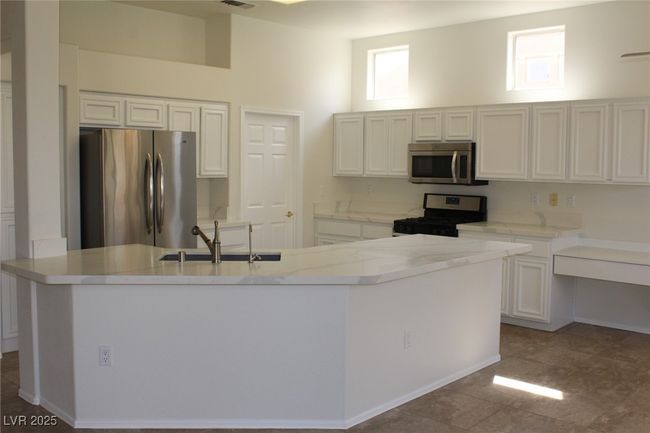 Kitchen with white cabinets, appliances with stainless steel finishes, a sink, and a kitchen island with sink | Image 8