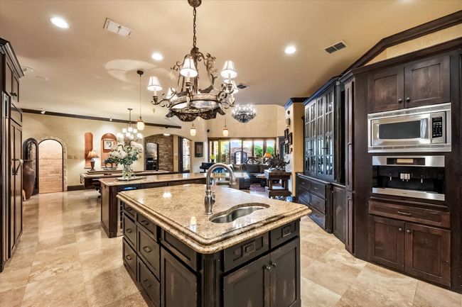 Kitchen with a kitchen island with sink, a chandelier, appliances with stainless steel finishes, and granite counters | Image 12