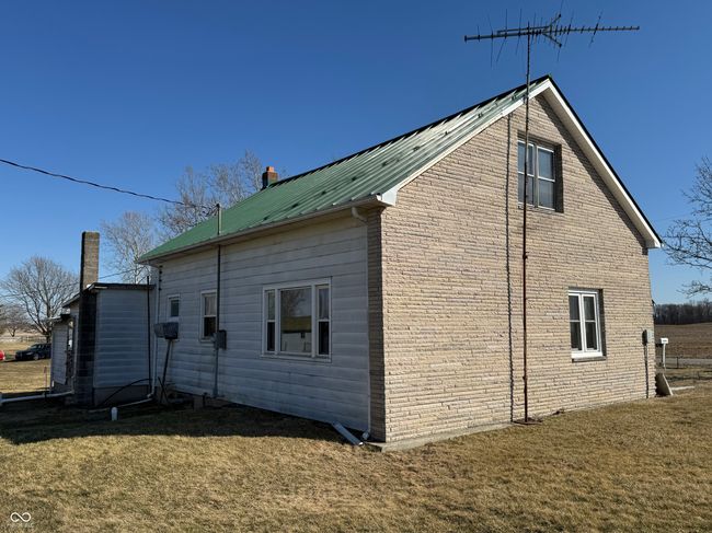 view of side of home with metal roof, brick siding, and a yard | Image 6