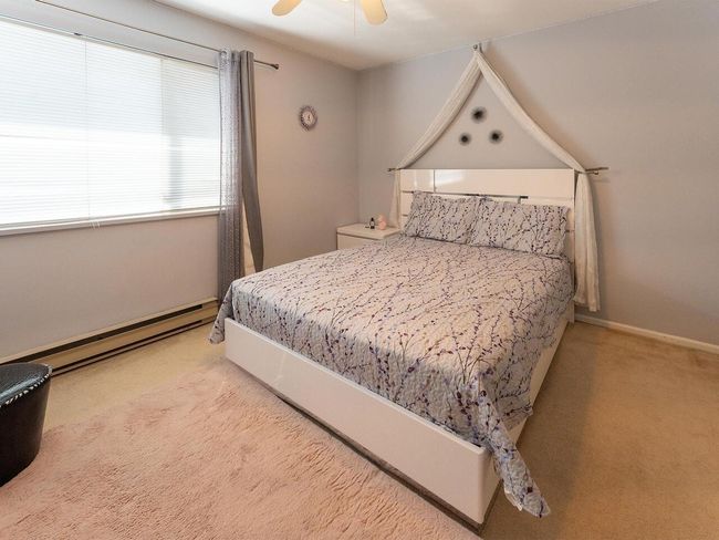 Bedroom featuring baseboards, ceiling fan, light carpet, and a baseboard radiator | Image 16