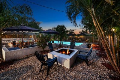 Patio terrace at dusk with a fenced in pool and an outdoor fire pit | Image 2