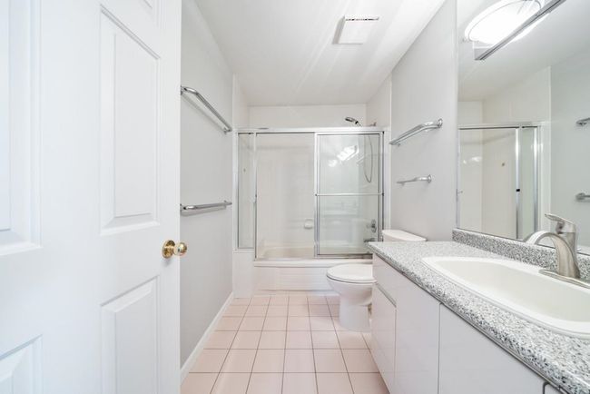 Full bathroom with enclosed tub / shower combo, toilet, tile patterned flooring, and vanity | Image 26