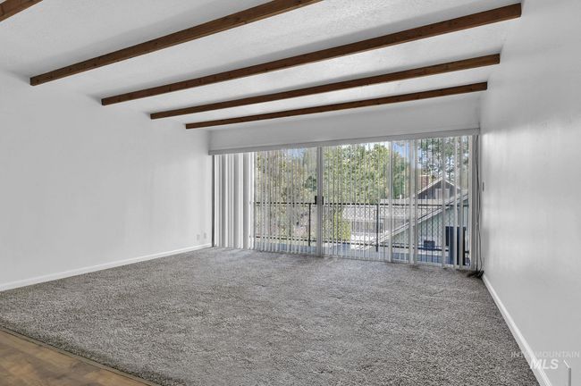 Unfurnished living room with beam ceiling and carpet flooring | Image 8