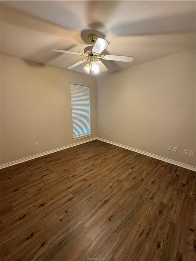 Spare room featuring dark wood-type flooring and a ceiling fan | Image 8