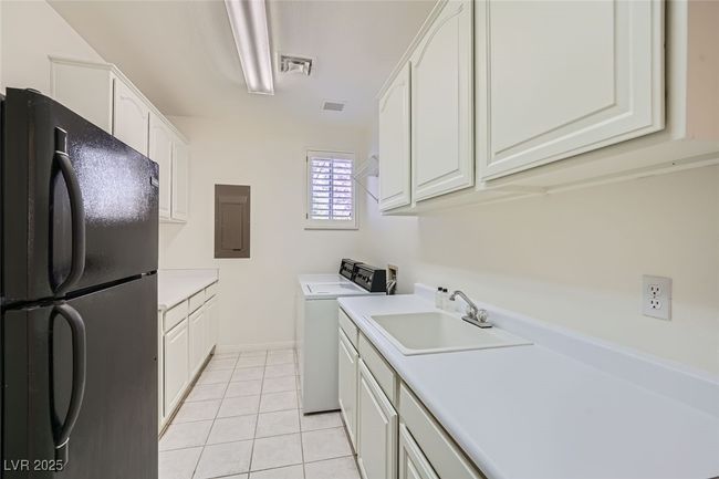Kitchen with electric panel, washer / clothes dryer, freestanding refrigerator, a sink, and light tile patterned flooring | Image 49