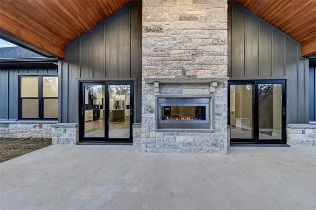 Unfurnished living room featuring an outdoor stone fireplace, concrete flooring, high vaulted ceiling, and wooden ceiling | Image 32