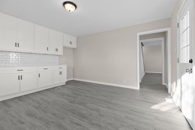 Kitchen with decorative backsplash, light wood-style flooring, white cabinetry, light countertops, and baseboards | Image 8